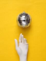 Disco ball and hand on yellow background. Minimalism party concept