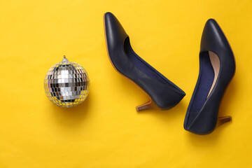 Disco ball with shoes on yellow background. Top view. Flat lay. Minimalism party concept