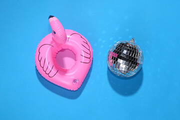 Inflatable flamingo with disco ball on blue background. Minimalism party concept. Top view