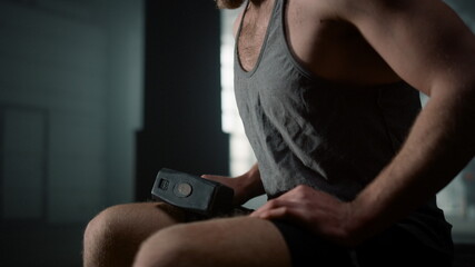 Man holding hammer for training in hand. Exhausted sportsman sitting on tire