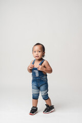 Asian boy wearing denim overalls is walking.