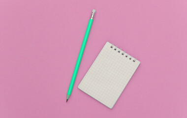 Notebook with pencil on pink pastel background. Top view