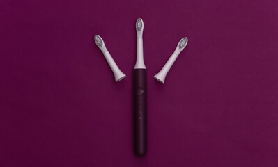 Electro toothbrush with replaceable heads on purple background. Top view