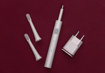 Electro-toothbrush with charger on red background. Top view