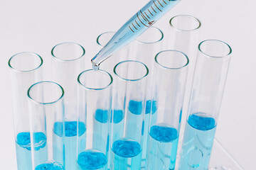Laboratory test tubes with blue reagent and pipette with drop. Medical research concept.