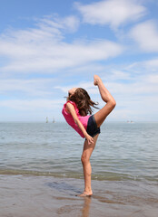 young girl doing rhythmic gymnastics exercises on the beach