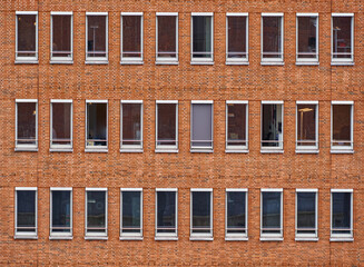 Monotonous facade of red bricks of a high-rise office building with long rectangular windows...