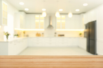 Fototapeta na wymiar Empty wooden table and blurred view of stylish kitchen interior. Mockup for design