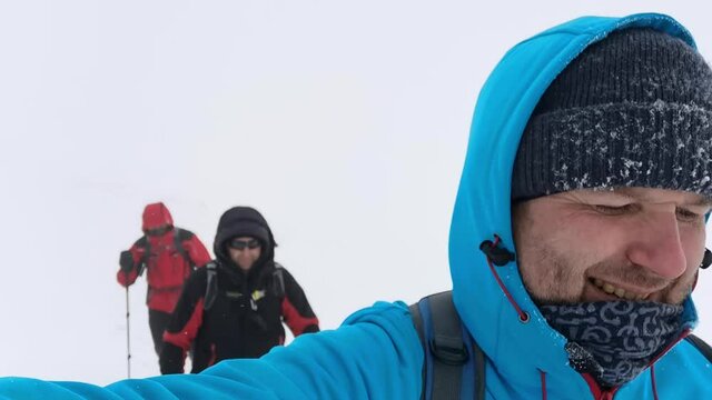 Tourists walk in the fog on a winter hike in the Carpathian Mountains. The man shoot selphie video