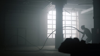 Man using battle ropes during workout in gym. Athlete doing crossfit exercise