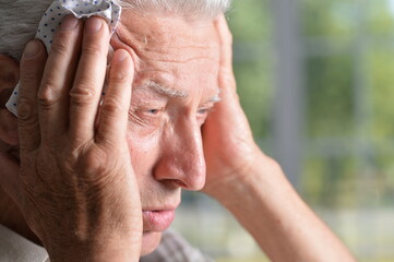 Portrait of sad sick senior man with headache