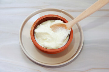 white milk yogurt in a wooden spoon and plate