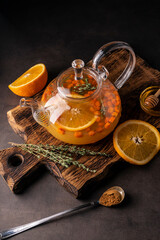 selective focus, freshly brewed sea buckthorn tea in a transparent teapot, with fruits and fresh...