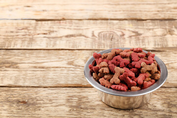 Dry pet food in bowl on brown wooden table