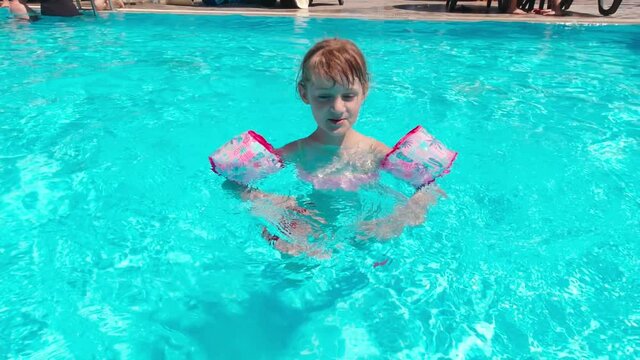 Girl in the pool with swimming armbands slow motion