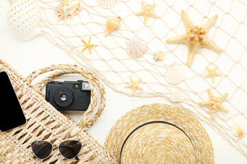 Starfishes with seashell, straw hat, sunglasses and retro camera on white wooden table