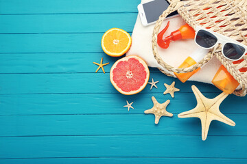 Summer bag with smartphone, fresh fruits and starfishes on blue wooden background