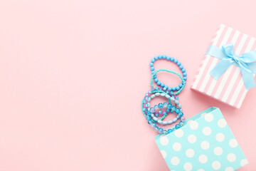 Blue bracelets with gift box on pink background