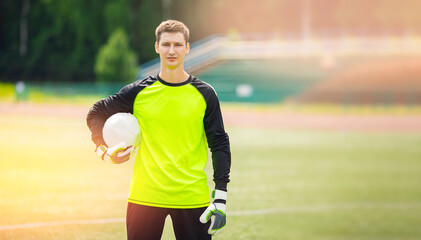 Portrait man goalkeeper with soccer ball in stadium sport sunlight