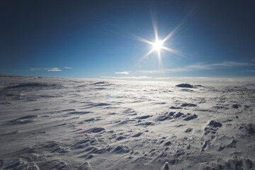 Snowy landscape with blue sky and a sunstar