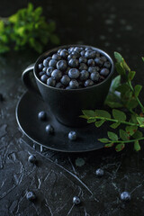 Fototapeta na wymiar blueberries in a cup, black background, gifts of the forest