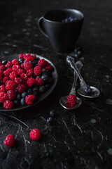 raspberries and blueberries, on a black background, wild berry