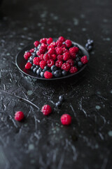 raspberries and blueberries, on a black background, wild berry