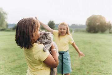 Children portrait with kitten in park. Girls playing outdoors with cat