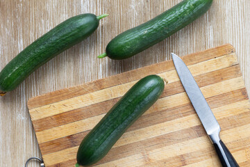 Top view of whole fresh cucumbers before cutting and peeling on the wooden cutting board