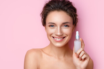 Woman holds hyaluronic serum. Photo of attractive woman with perfect makeup on pink background. Beauty concept