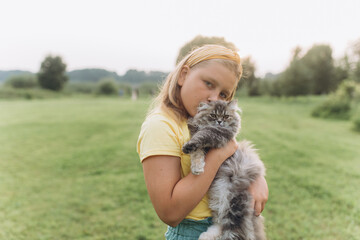 Portrait with kitten in park. Girl play outdoors with cat
