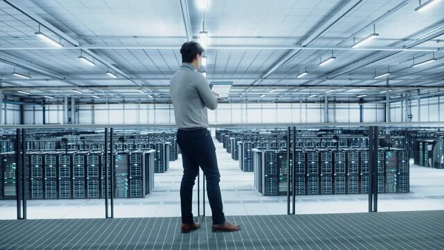 Data Center Engineer Using Laptop Computer. Server Farm Cloud Computing Specialist Facility with Asian Male System Administrator Working with Data Protection Network for Cyber Security.