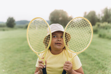 Summer outdoor children activity with tennis racket on green grass 