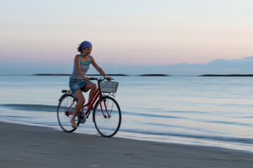 Fototapeta na wymiar Young woman during a bicycle trip at the beach early in the morning