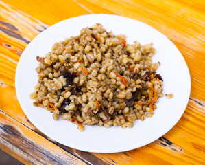 pearl barley porridge with mushrooms on a white plate