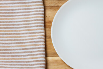 Kitchen accessories. Salt and pepper shaker, kitchen towel. Black ceramic knife, white plate. Fork and cutting board.