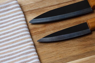 Kitchen accessories. Salt and pepper shaker, kitchen towel. Black ceramic knife, white plate. Fork and cutting board.
