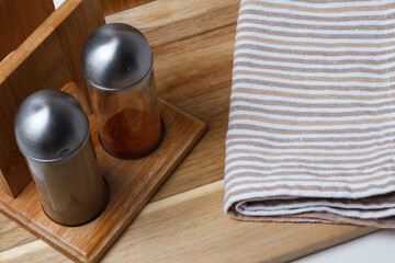 Kitchen accessories. Salt and pepper shaker, kitchen towel. Black ceramic knife, white plate. Fork and cutting board.