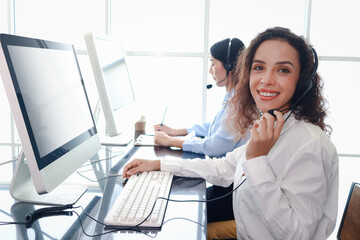 Smiling beautiful woman with headphones work at call center service desk consultant, call center...