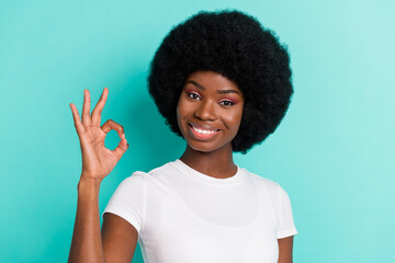 Photo of cheerful young dark skin woman make okay sign smile advert promoter isolated on teal color background