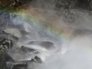 Regenbogen im Wasserfall vor Felsen