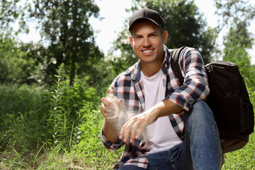 Man spraying tick repellent on arm during hike in nature