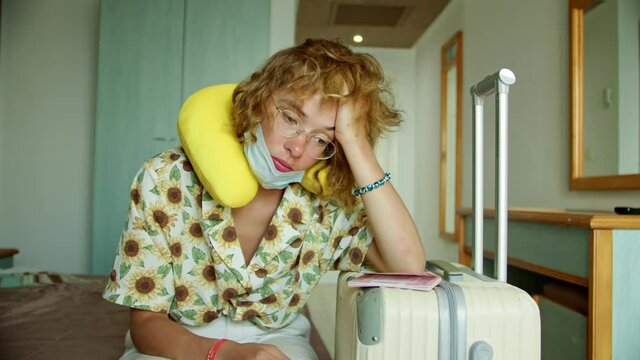 a woman in a hotel room wearing a protective mask and with a suitcase, immediately after the airport to the hotel for quarantine. vacation problem due to coronavirus test