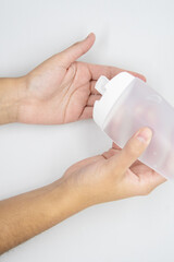 Hands using a plastic bottle of sanitizer