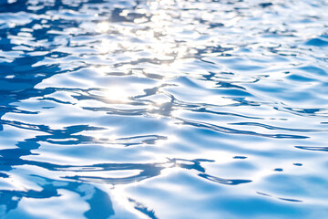Blue water surface in the pool with the glare of the sun.Creative background.
