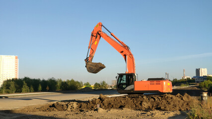 Fototapeta na wymiar Yellow excavator machine during excavation work on construction site. Process of building new road or urban highway