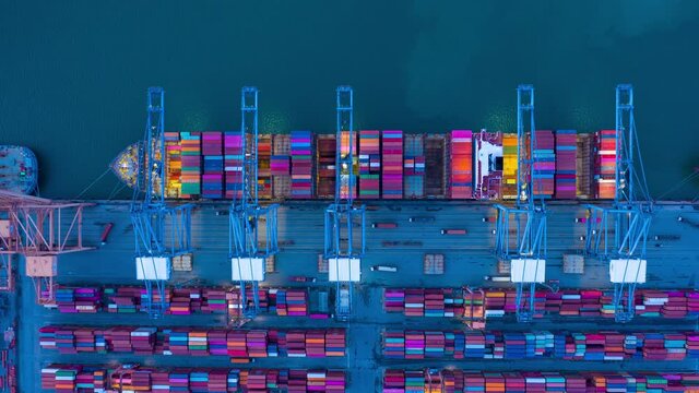 Time lapse of Aerial top view over container cargo ship at industrial import-export port prepare to load containers with big container loader ship vessel. global transportation and logistic business.