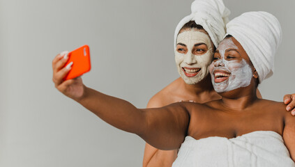 Happy girlfriends taking selfie during spa session