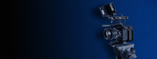 Digital video camera on dark blue background with copy space. Movie production or brodcasting...