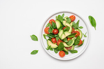 Spinach avocado tomatoes salad. Healthy vegan food. White background, top view, copy space